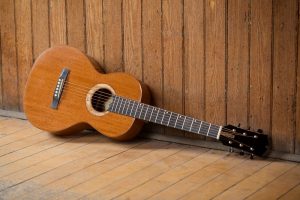 Parlor Guitar against a wood wall | Kazourian Luthier Montréal